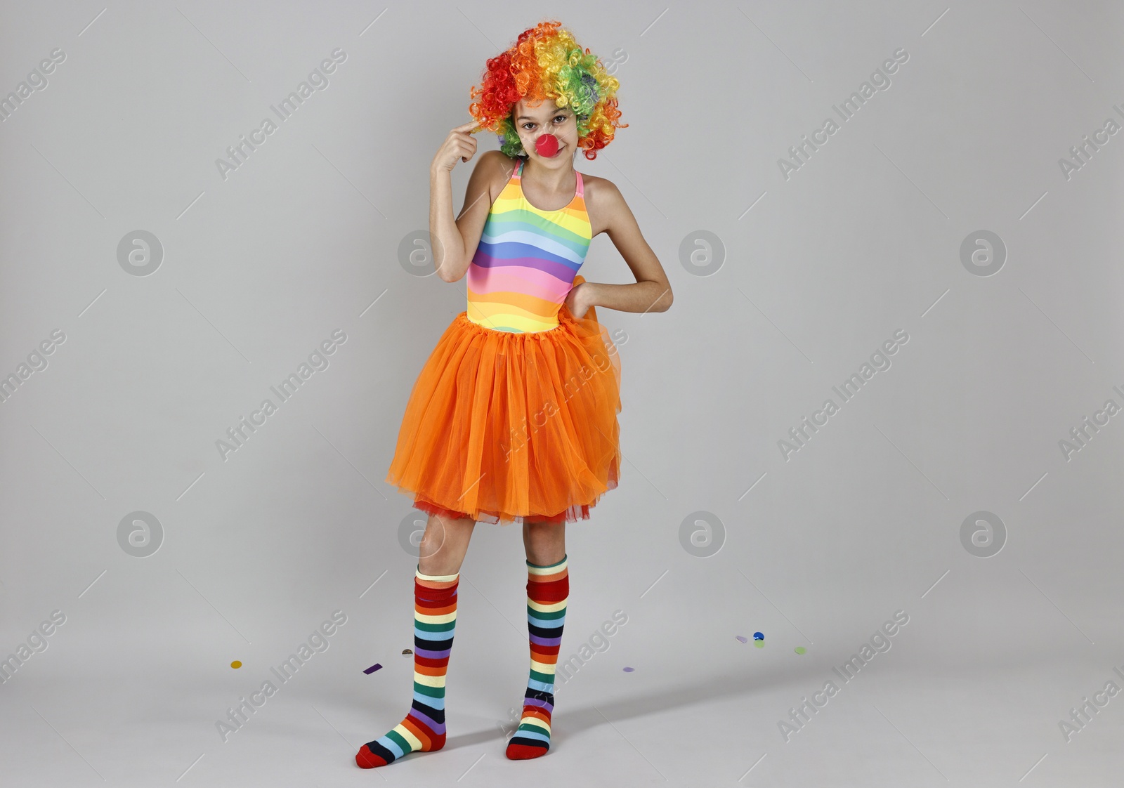 Photo of Cute girl dressed like clown on grey background. Surprise party