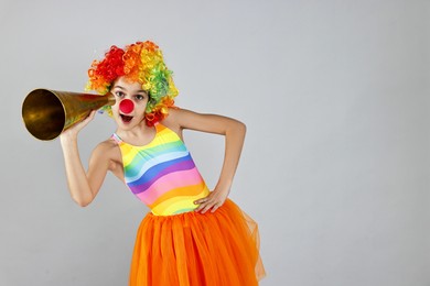 Photo of Girl dressed like clown with megaphone on grey background, space for text. Surprise party