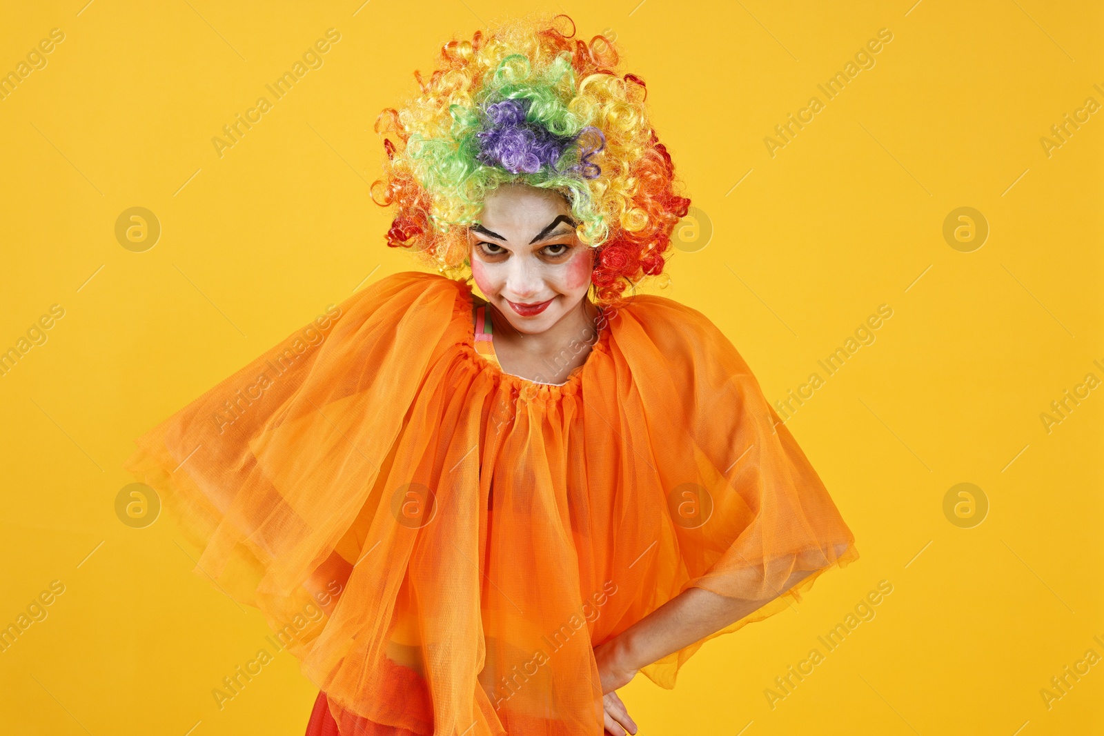 Photo of Cute girl dressed like clown on yellow background. Surprise party