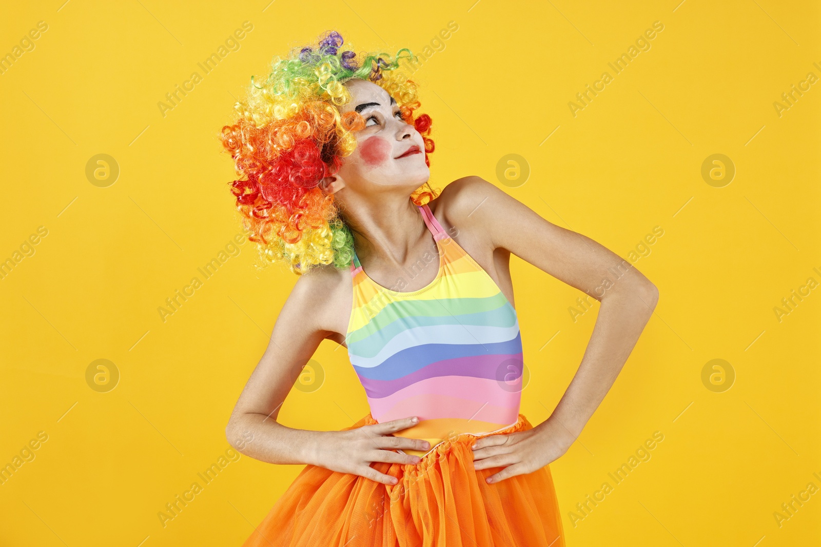 Photo of Cute girl dressed like clown on yellow background. Surprise party