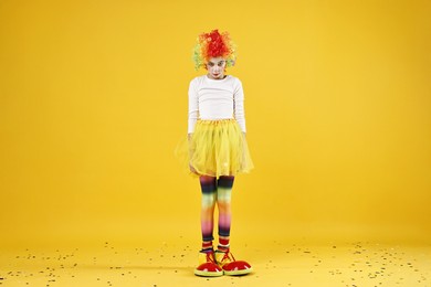 Photo of Cute girl dressed like clown on yellow background. Surprise party