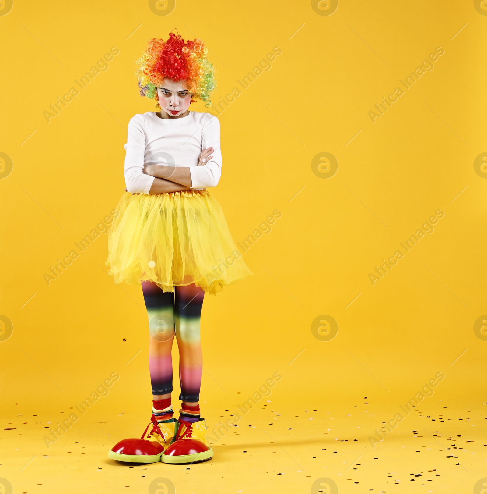 Photo of Cute girl dressed like clown on yellow background, space for text. Surprise party