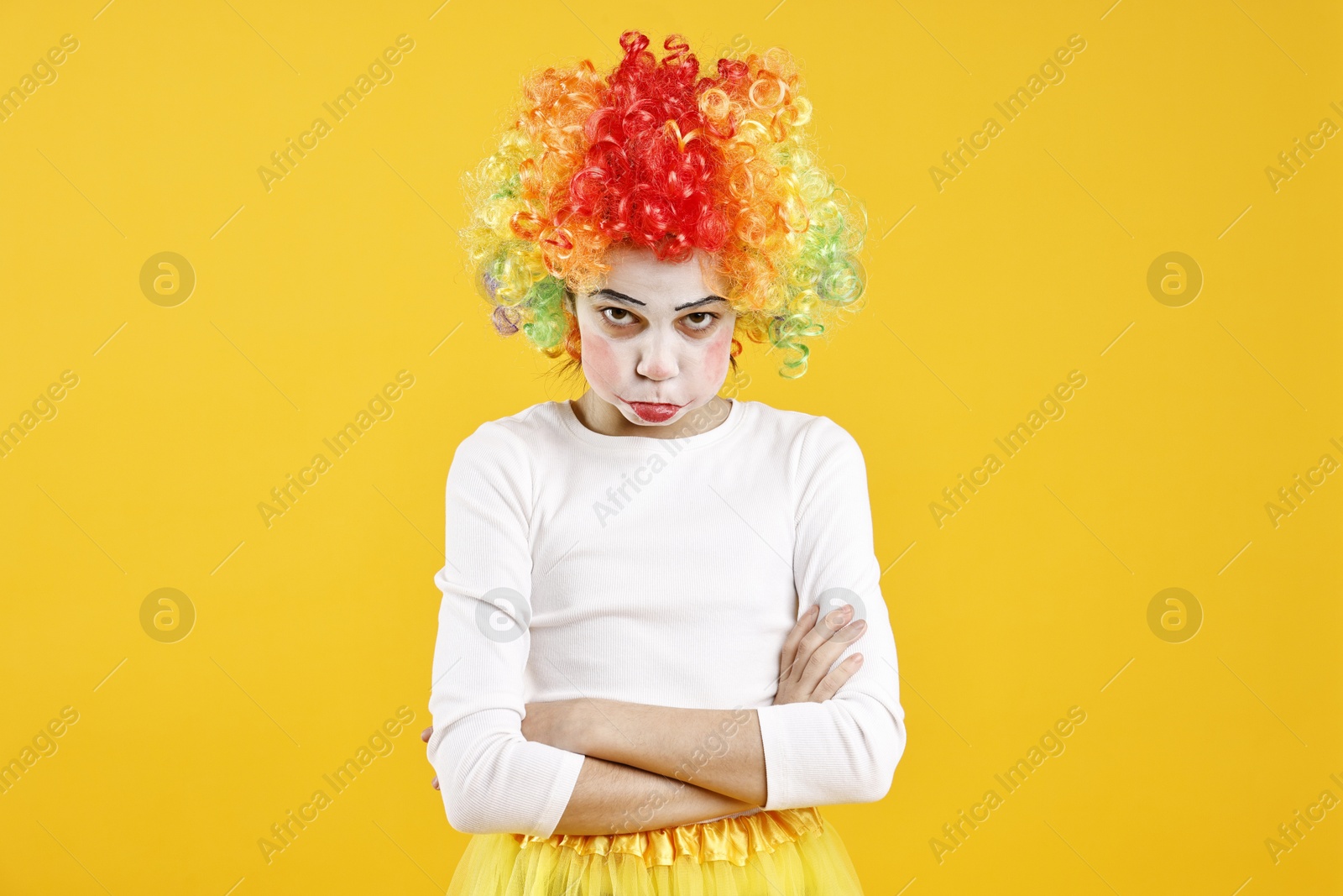 Photo of Cute girl dressed like clown on yellow background. Surprise party