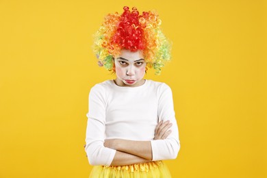 Cute girl dressed like clown on yellow background. Surprise party