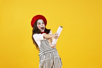 Photo of Happy girl dressed like mime with confetti popper on yellow background. Surprise party