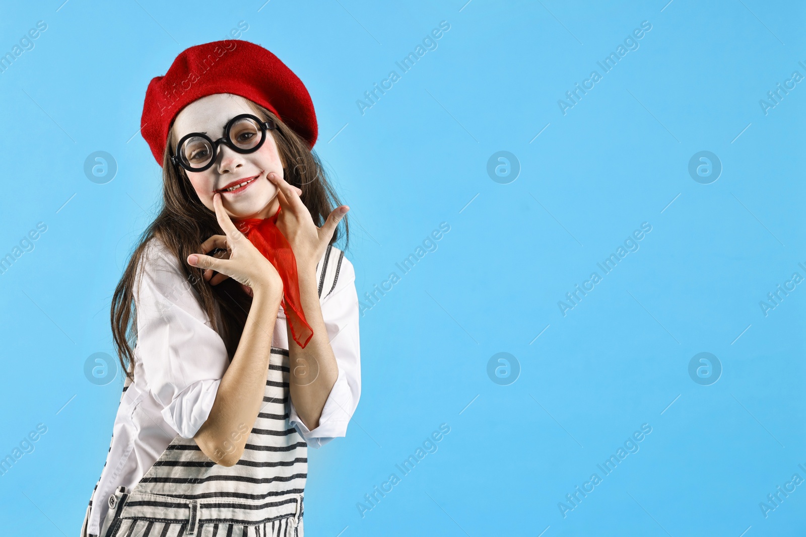 Photo of Happy girl dressed like mime on light blue background, space for text. Surprise party