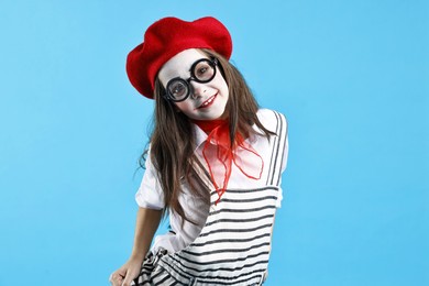 Photo of Happy girl dressed like mime on light blue background. Surprise party