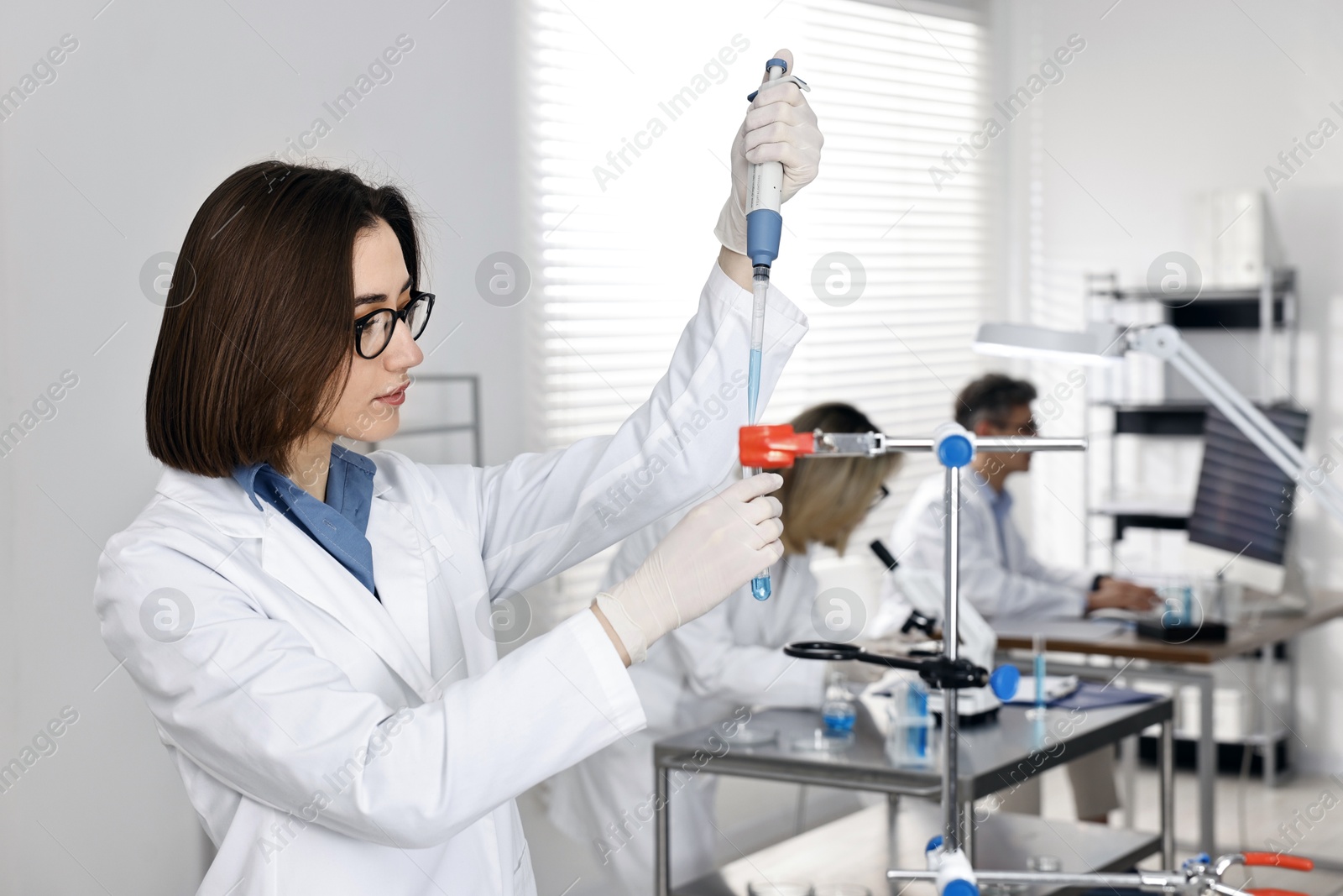 Photo of Scientist with micropipette and test tube working in laboratory