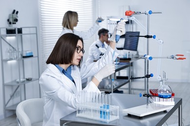 Photo of Scientist with micropipette and test tube working in laboratory