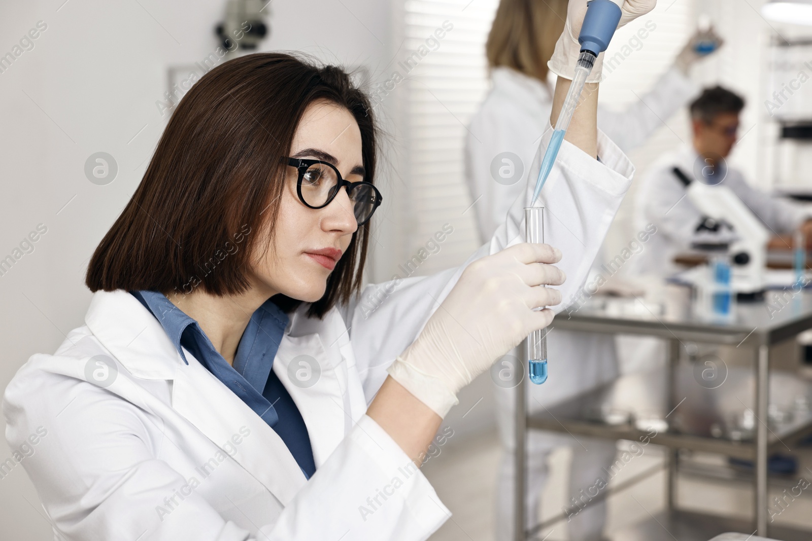 Photo of Scientist with micropipette and test tube working in laboratory