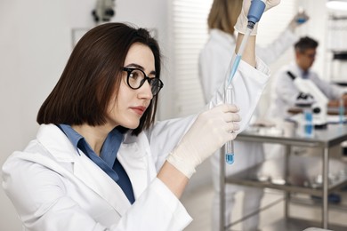 Photo of Scientist with micropipette and test tube working in laboratory