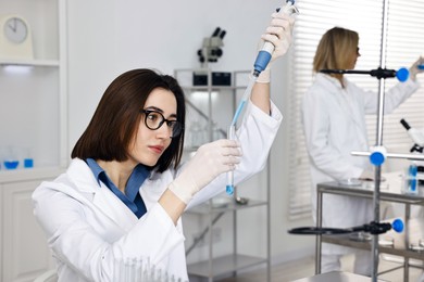 Photo of Scientist with micropipette and test tube working in laboratory