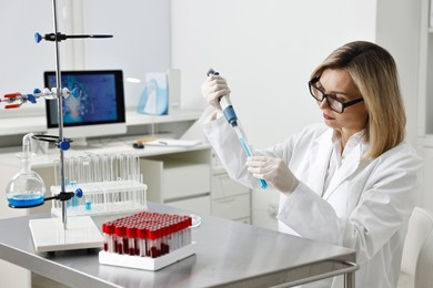 Photo of Scientist with micropipette and test tube working in laboratory