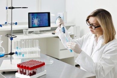 Photo of Scientist with micropipette and test tube working in laboratory