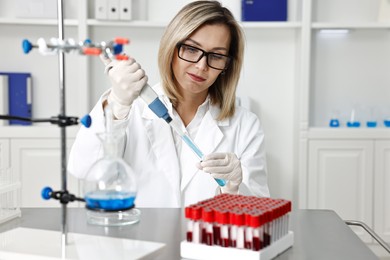 Photo of Scientist with micropipette and test tube working in laboratory