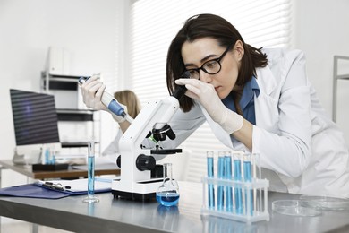 Photo of Scientist working with microscope and glassware in laboratory