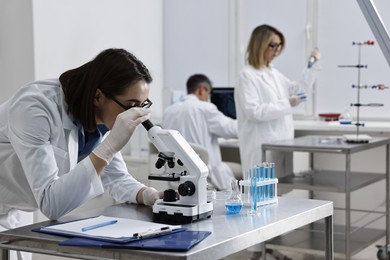 Scientist working with microscope at table in laboratory