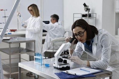 Photo of Scientist working with microscope at table in laboratory