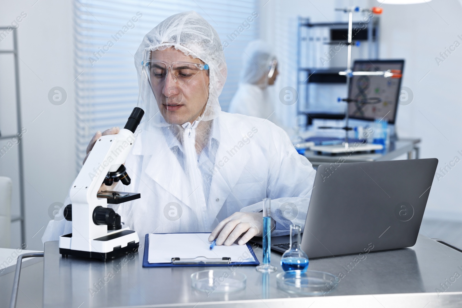 Photo of Scientist with laptop and microscope working at table in laboratory