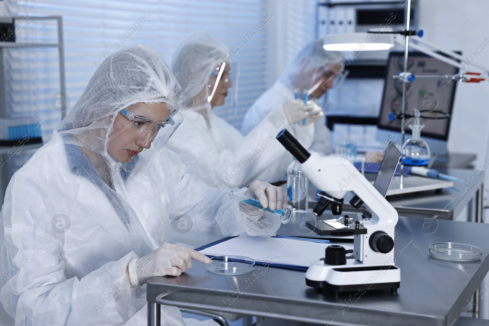 Photo of Scientist with glassware and microscope working at table in laboratory