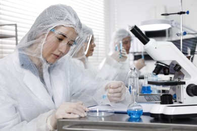 Scientist dripping sample into Petri dish at table in laboratory