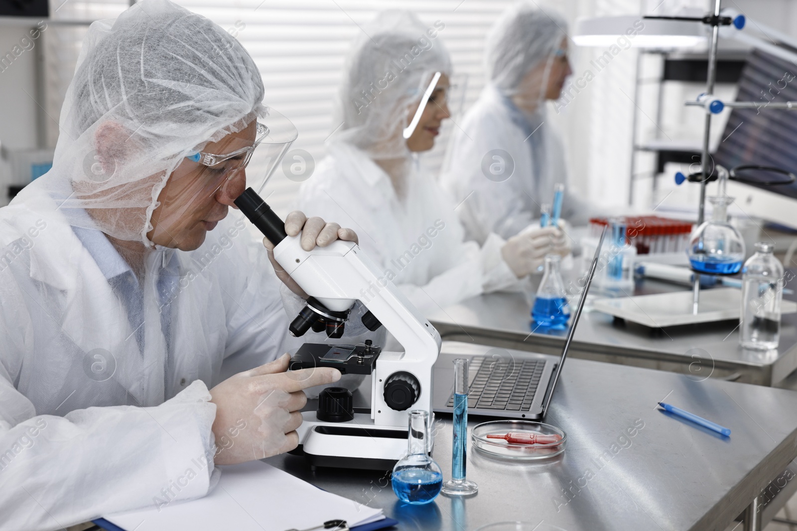 Photo of Scientist working with microscope at table in laboratory