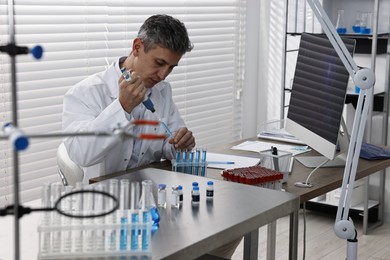 Photo of Scientist with micropipette and test tubes working in laboratory