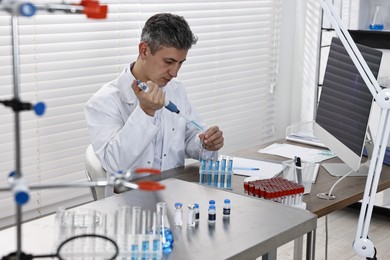 Photo of Scientist with micropipette and test tubes working in laboratory