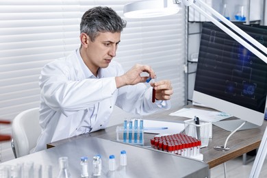 Photo of Scientist with test tubes working in laboratory