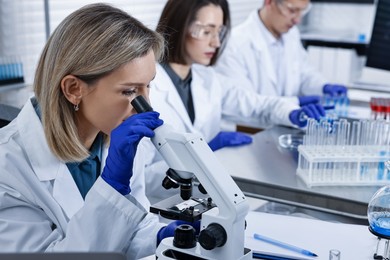 Photo of Scientist working with microscope at table in laboratory