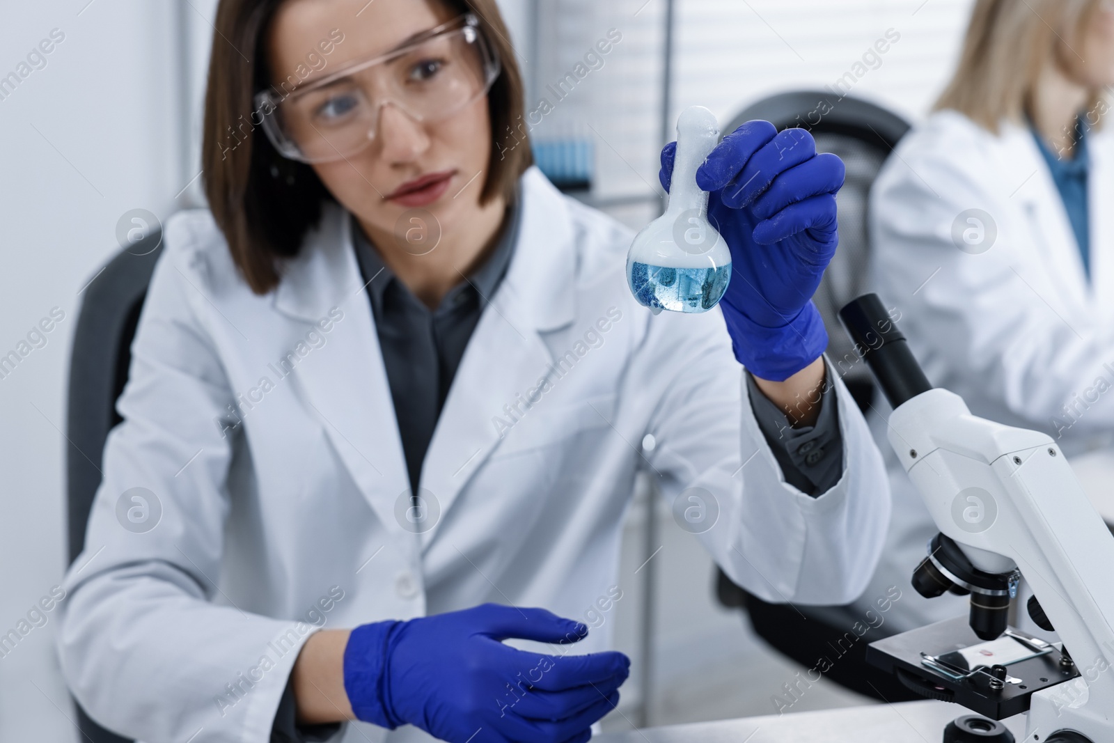 Photo of Scientist holding flask with sample in laboratory, selective focus