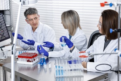 Photo of Scientists working with computer and samples at table in laboratory