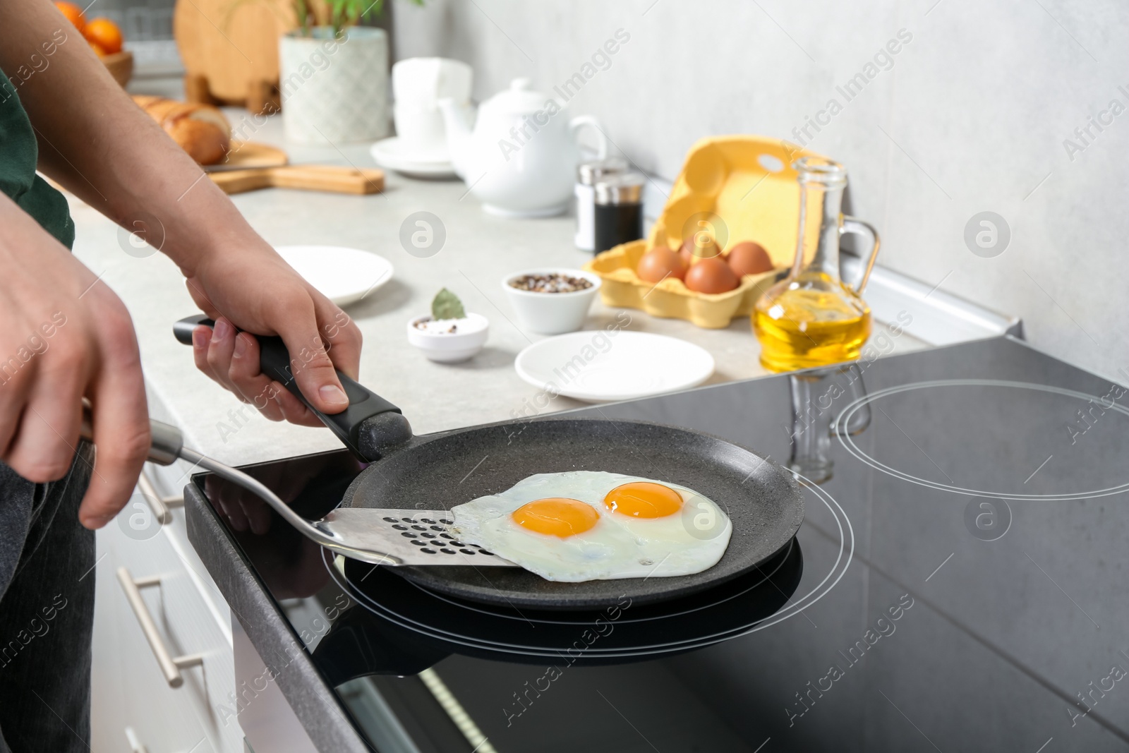 Photo of Man taking fried eggs from frying pan in kitchen, closeup