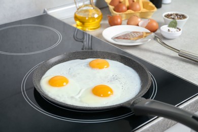 Photo of Cooking tasty eggs on frying pan in kitchen, closeup