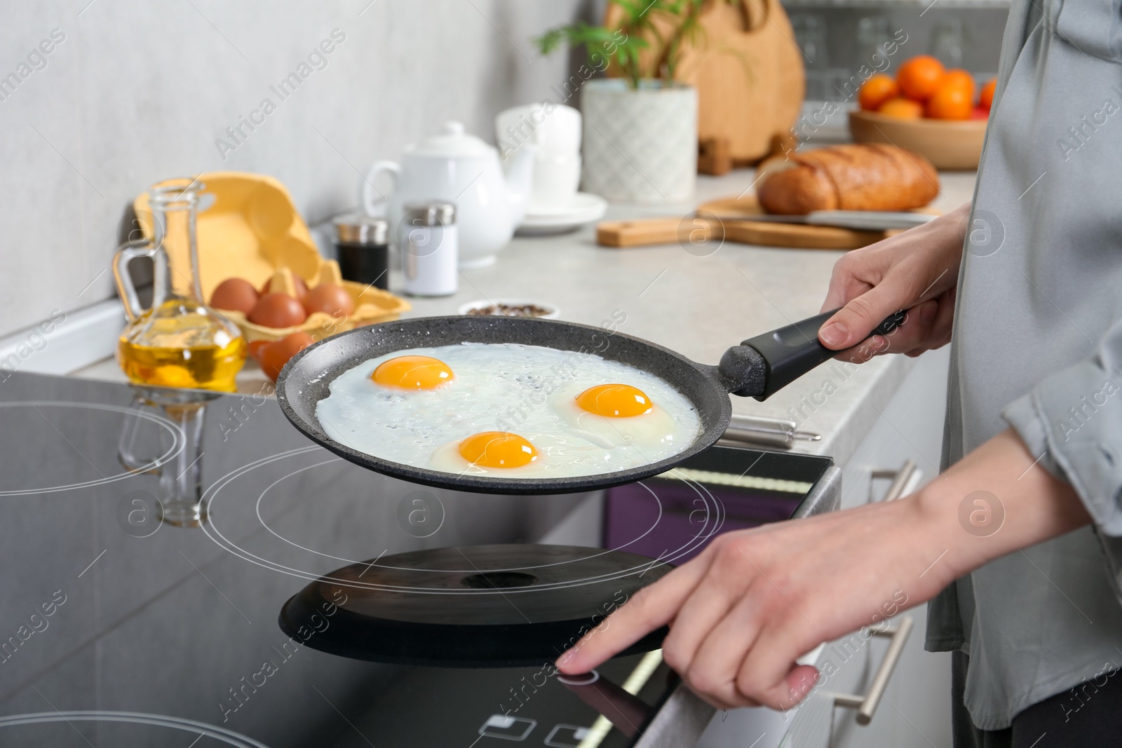 Photo of Woman cooking eggs in frying pan on cooktop indoors, closeup