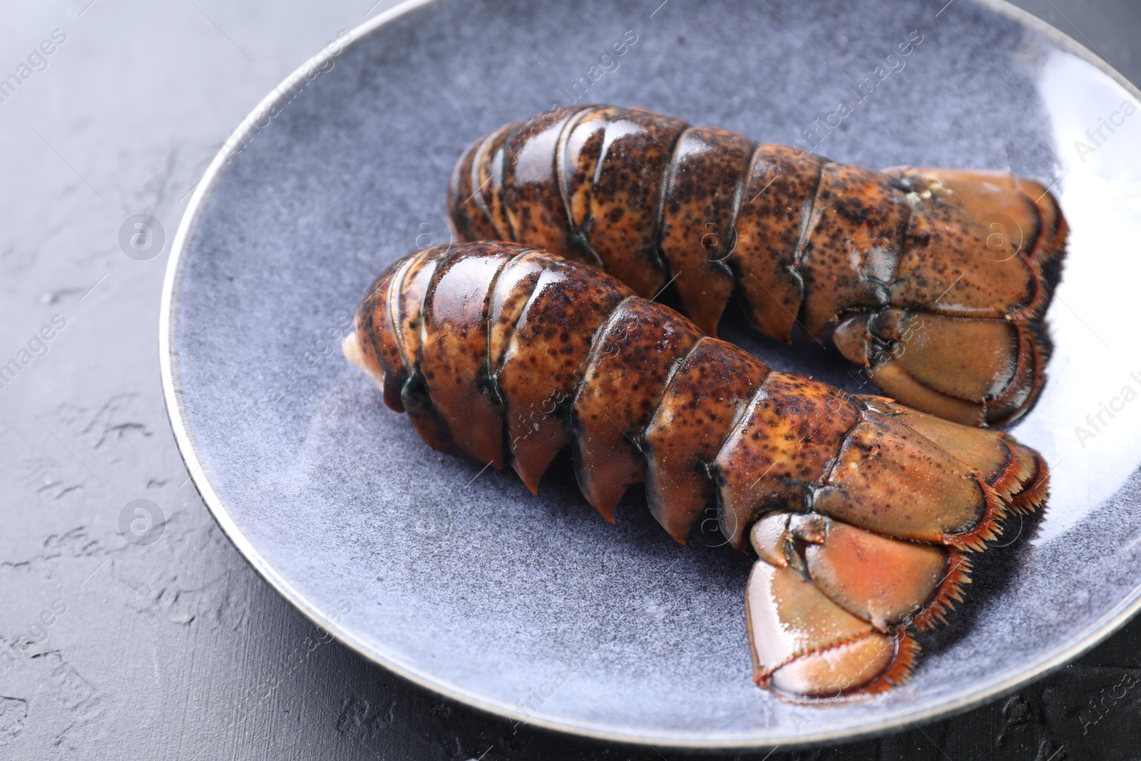 Photo of Raw lobster tails on black table, closeup