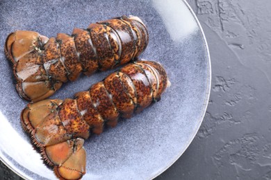 Raw lobster tails on black table, top view