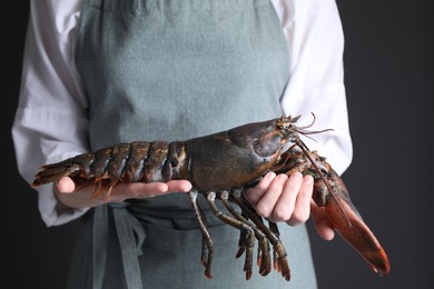 Photo of Woman with raw lobster on black background, closeup