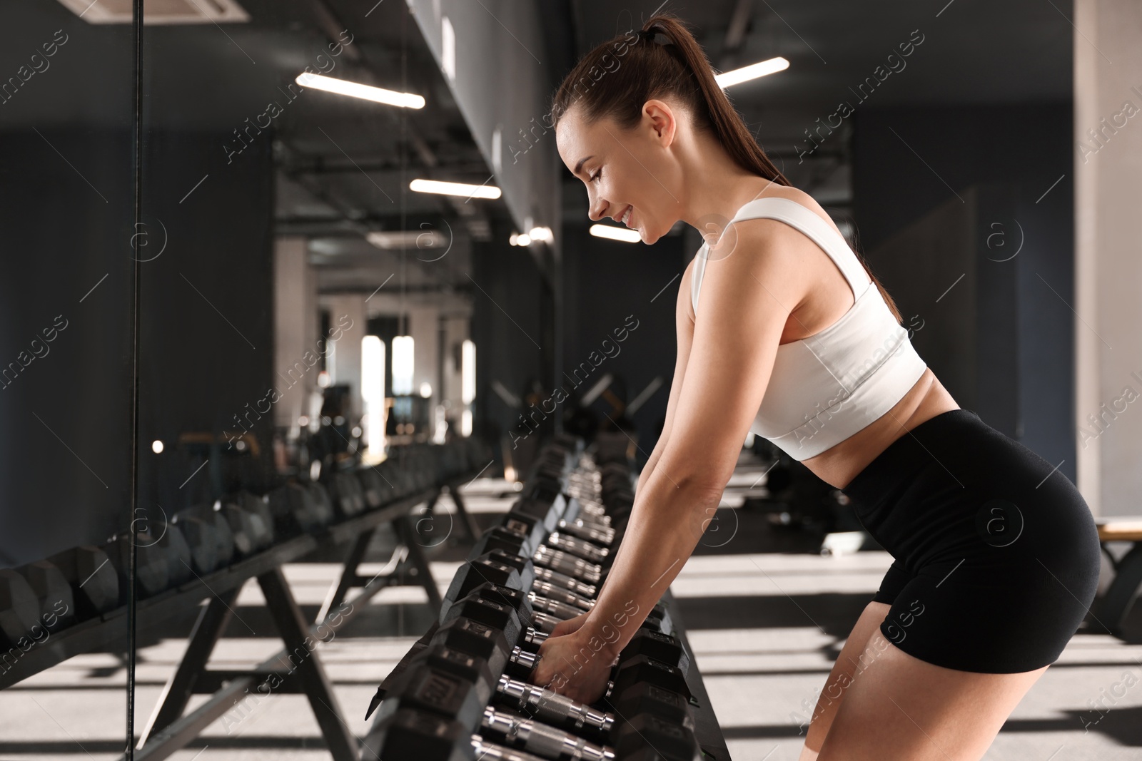 Photo of Sportswoman with dumbbells during crossfit workout in gym. Space for text