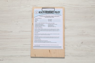 Health insurance policy form on light wooden table, top view