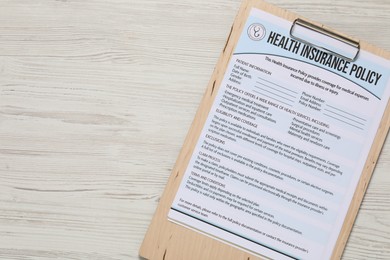 Photo of Health insurance policy form on light wooden table, top view. Space for text