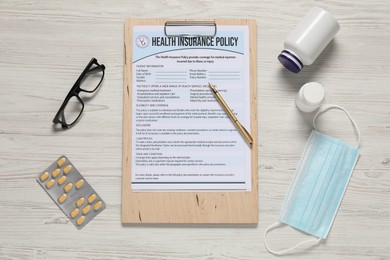 Flat lay composition with health insurance policy form on light wooden table