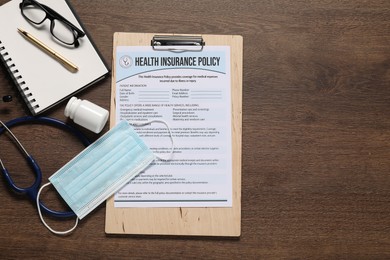 Photo of Flat lay composition with health insurance policy form on wooden table, space for text