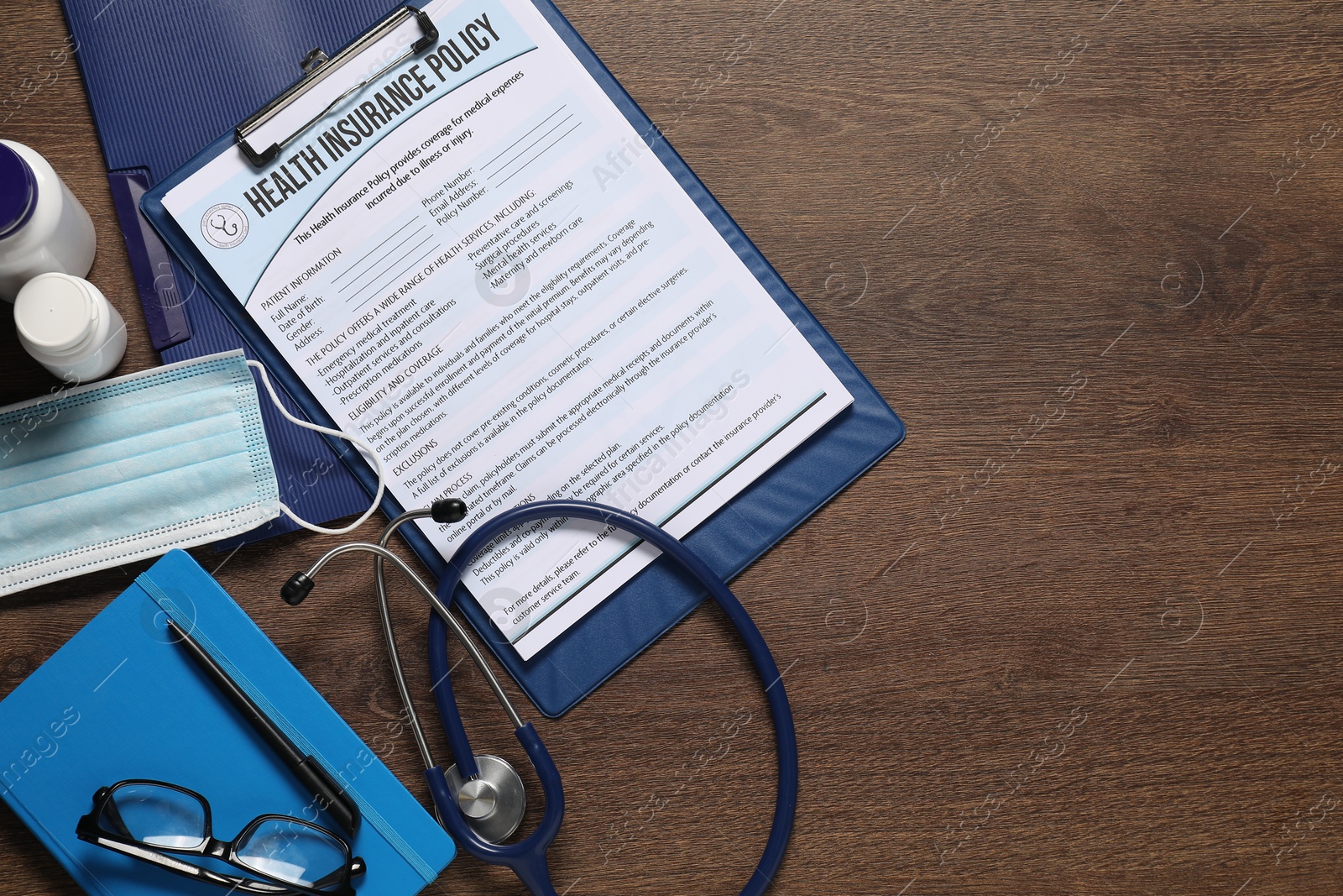 Photo of Flat lay composition with health insurance policy form on wooden table, space for text