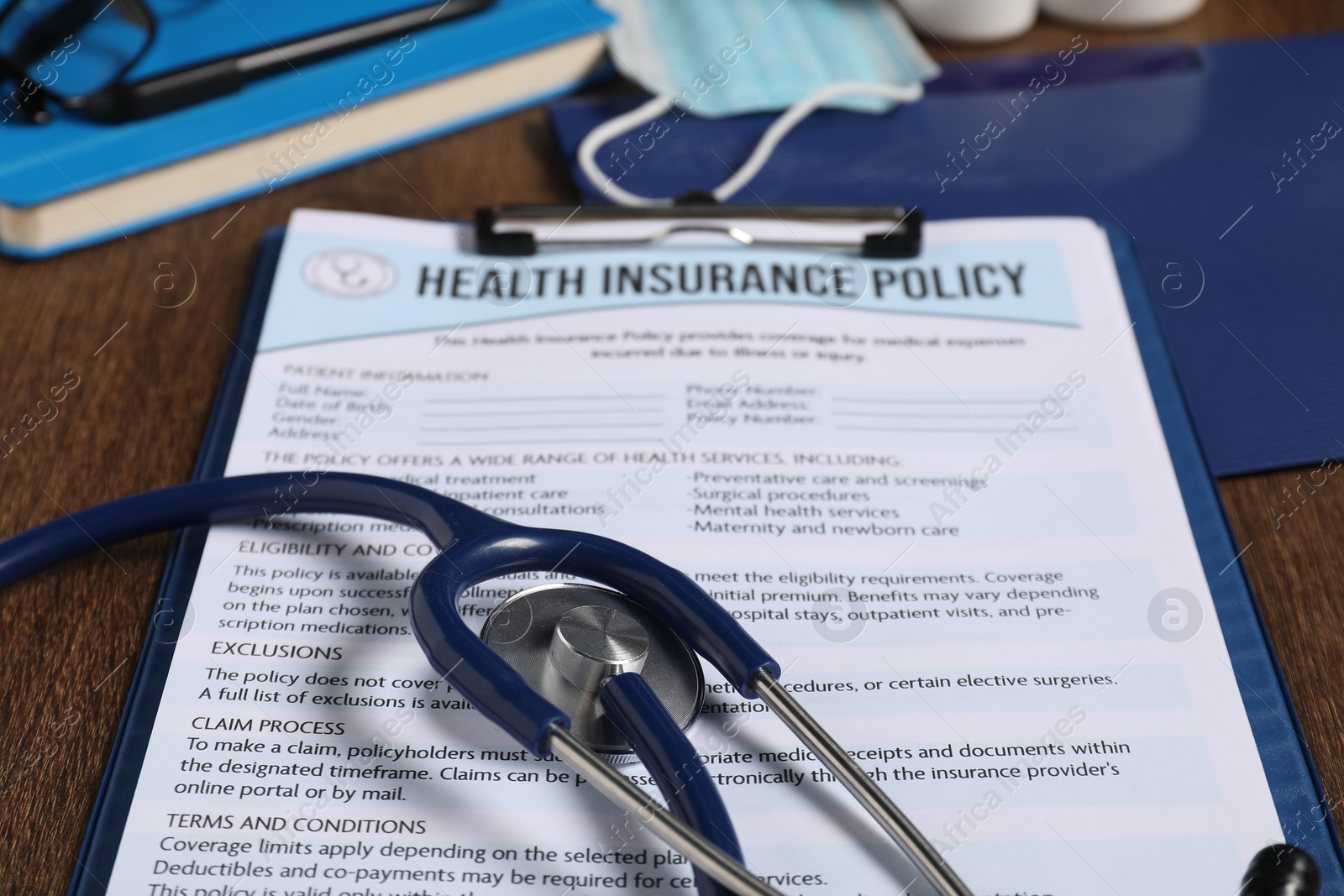 Photo of Health insurance policy form and stethoscope on wooden table, closeup