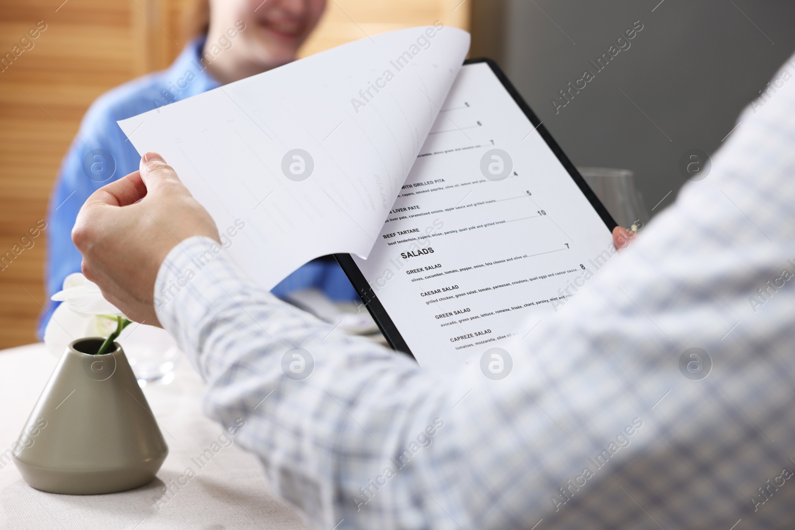 Photo of Couple choosing dishes from menu at table in restaurant, closeup