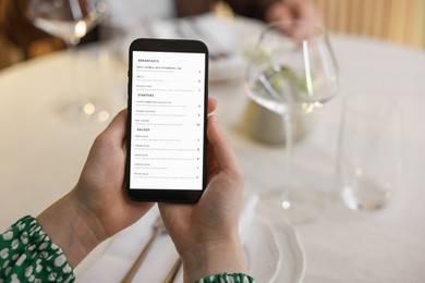 Photo of Woman choosing dishes from digital menu at restaurant, closeup