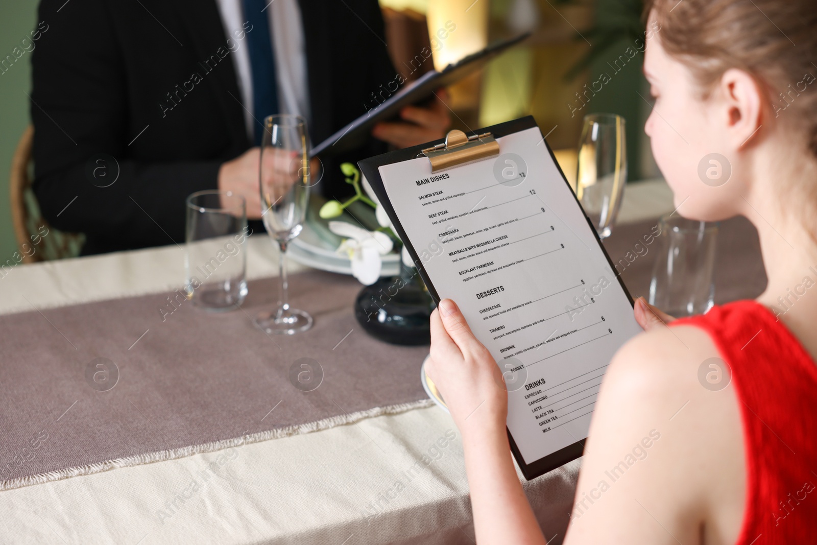 Photo of Couple choosing dishes from menu at table in restaurant, closeup