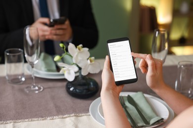 Photo of Couple choosing dishes from digital menu at restaurant, closeup