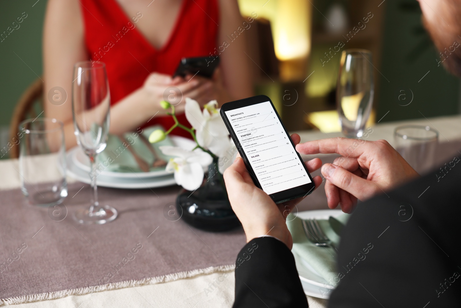 Photo of Couple choosing dishes from digital menu at restaurant, closeup